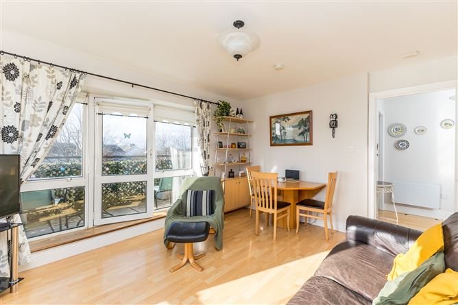 Bright living room with wood floors, seating area, and balcony view.