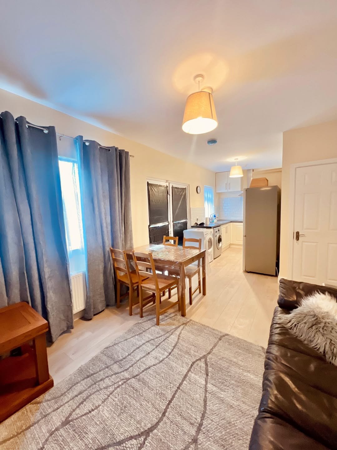 Bright living room with dining set, gray sofa, and kitchen view.
