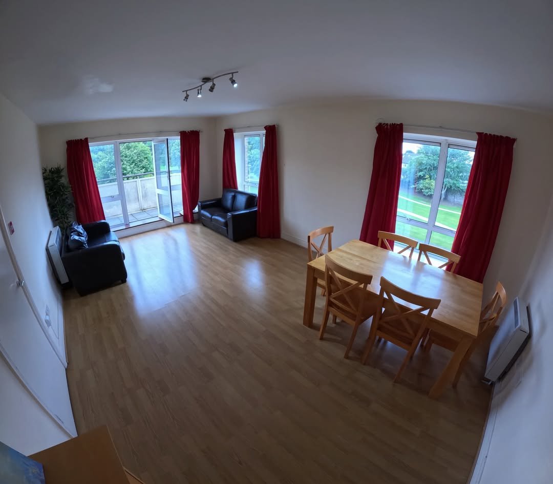 Bright living room with dining table, sofas, and red curtains.