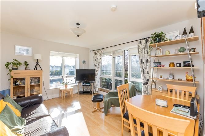 Bright living room interior with leather sofa, TV, shelving, and dining area.