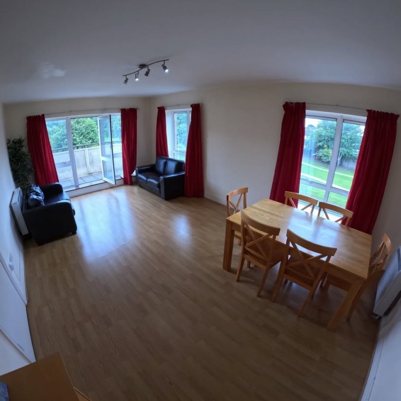 Bright living room with wood floors, red curtains, and modern furniture.