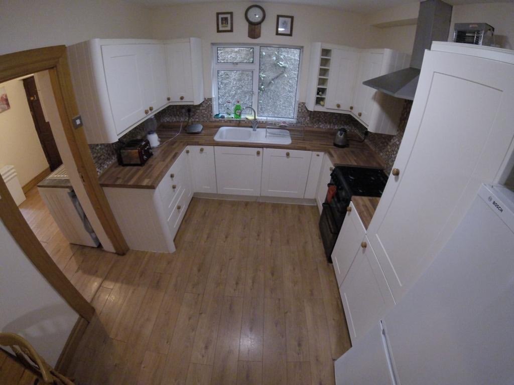 Bright kitchen with white cabinets, wood countertops, and light wood flooring.