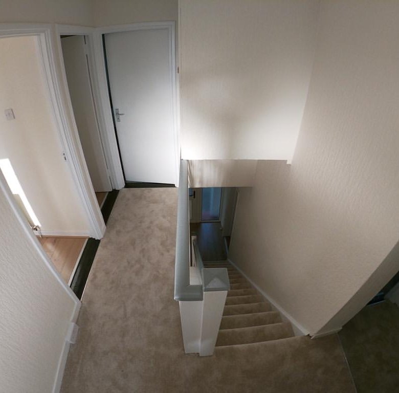 Hallway landing with carpeted stairs and open doorways.