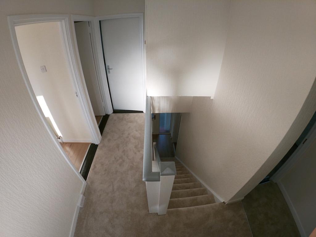 Hallway landing with carpeted stairs and open doorways.