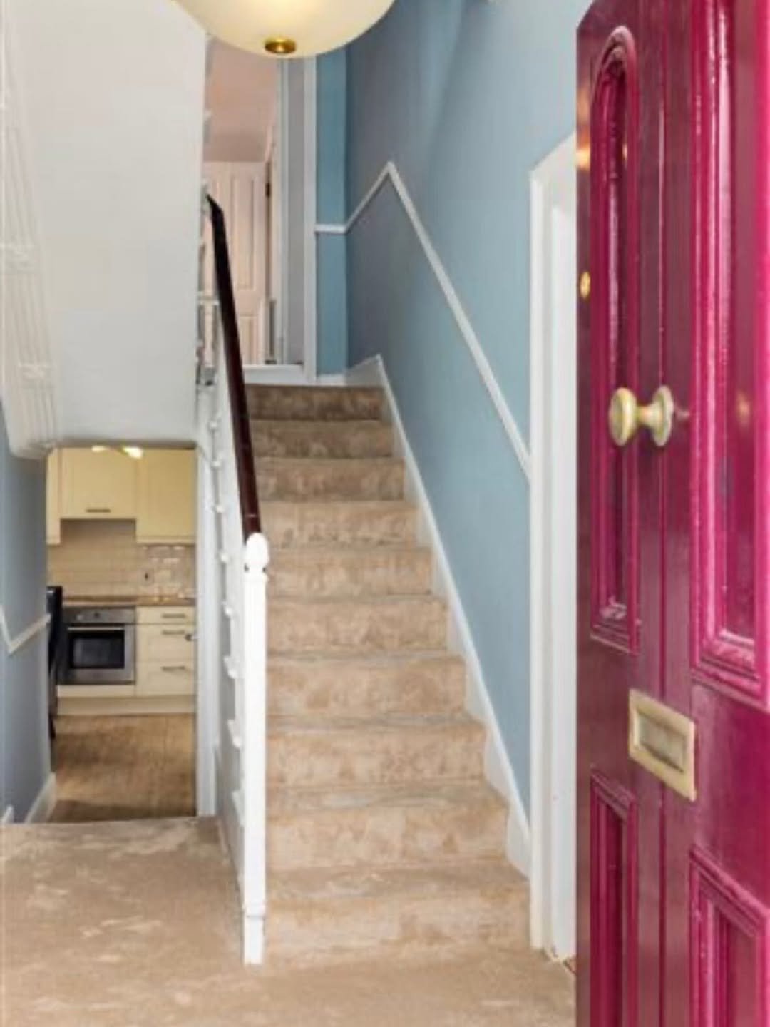 Entryway with carpeted stairs, blue walls, white trim, and a burgundy front door.