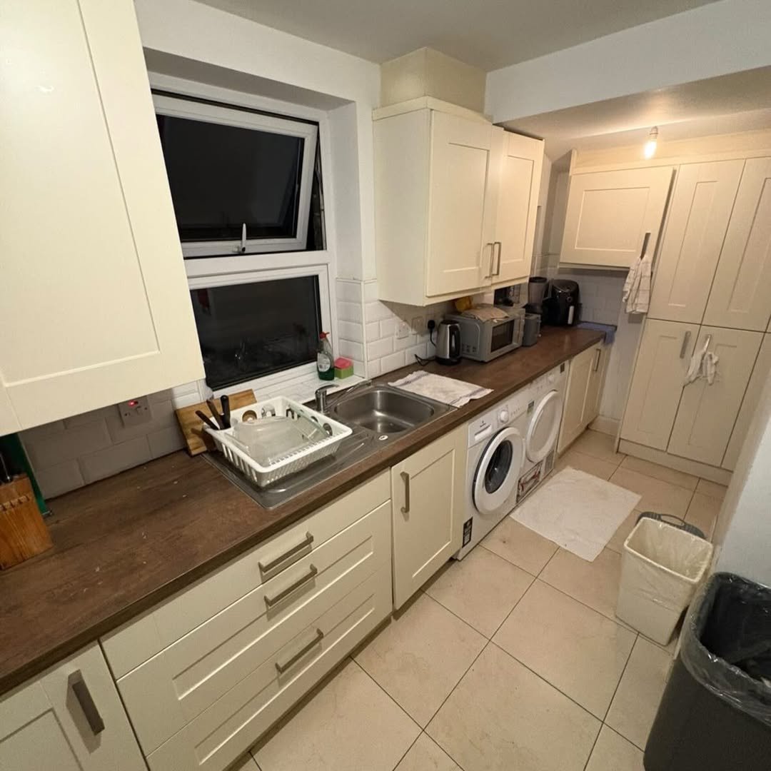 Compact kitchen with cream cabinets, wood countertops, and appliances.