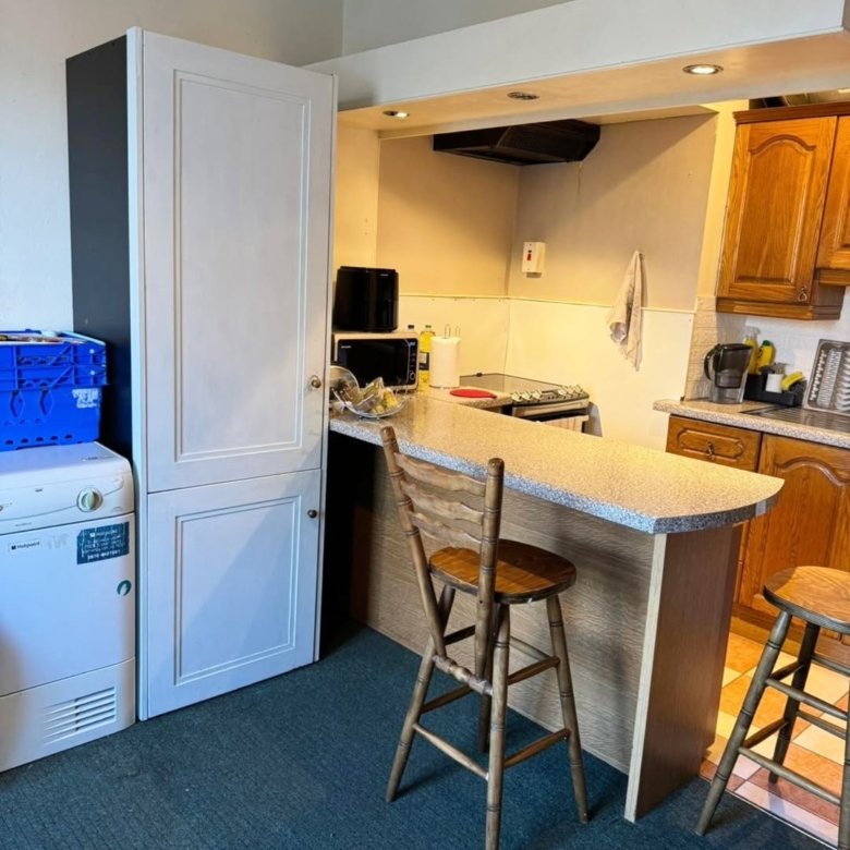 Compact kitchen with breakfast bar, white cabinets, and appliances.