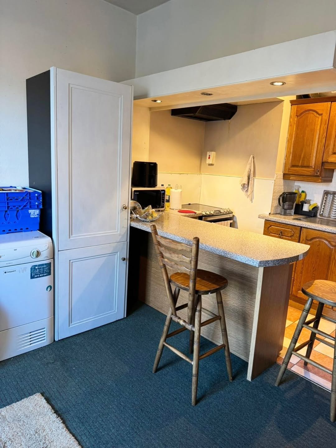 Compact kitchen with breakfast bar, white cabinets, and appliances.