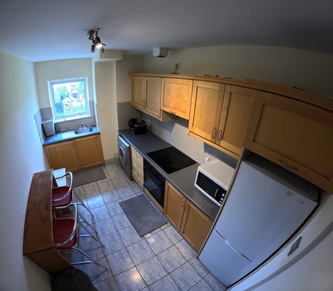 Compact kitchen with wood cabinets, gray countertops, and bar seating.