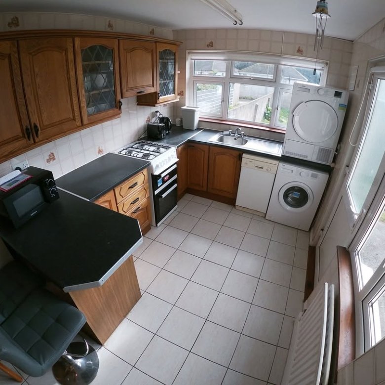 Compact kitchen with wood cabinets, appliances, and tile flooring.