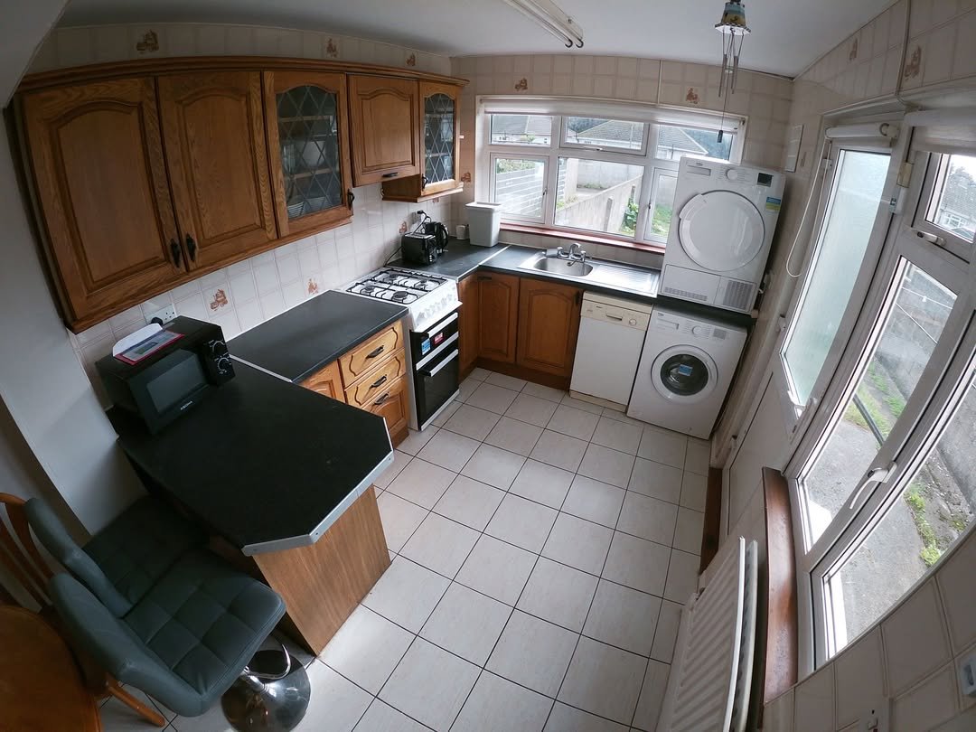 Compact kitchen with wood cabinets, appliances, and tile flooring.