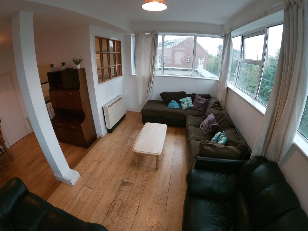 Cozy living room with brown sectional, wood floors, and large windows.