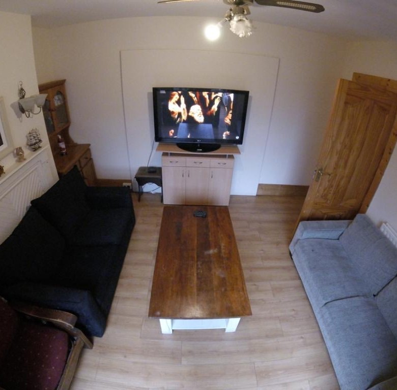 Cozy living room with sofas, wooden table, and TV displaying a performance.