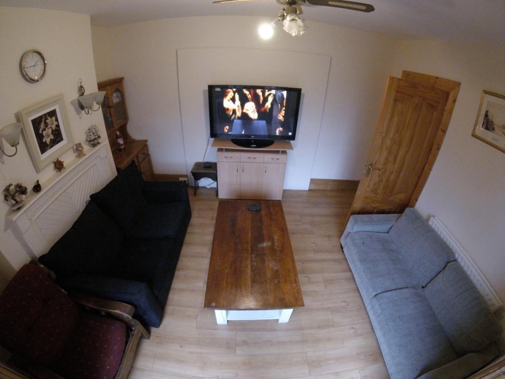 Cozy living room with sofas, wooden table, and TV displaying a performance.