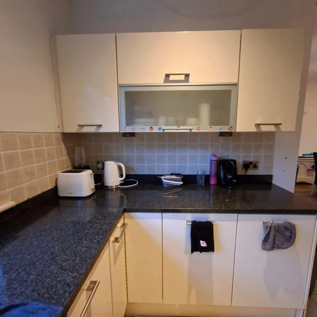 Kitchen corner with cream cabinets, speckled countertop, and small appliances.