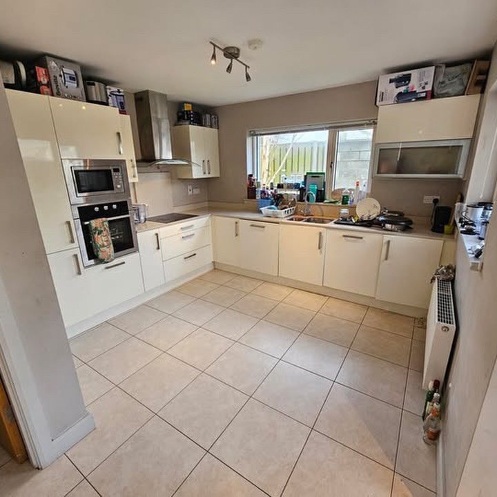 Bright kitchen with cream cabinets and tile flooring, window view, and appliances.