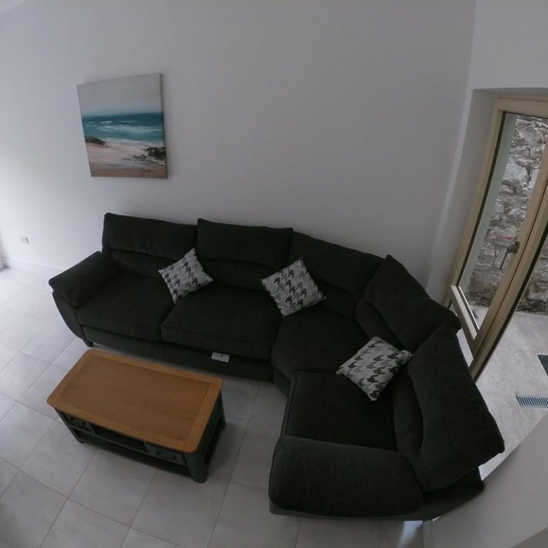 Living room with dark gray sectional sofa, coffee table, and coastal art.