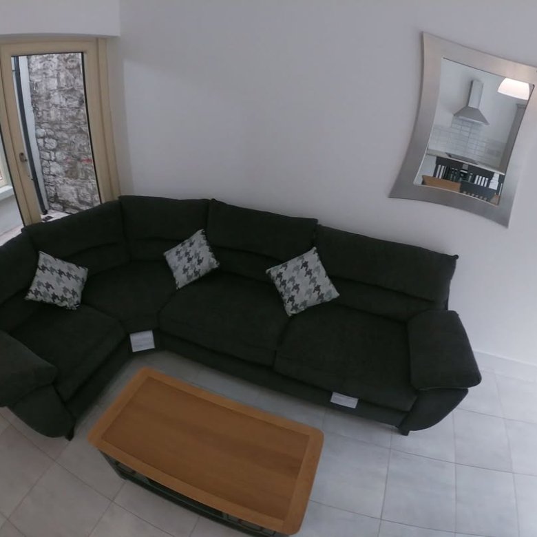 Living room with dark green sectional sofa, coffee table, and mirror.