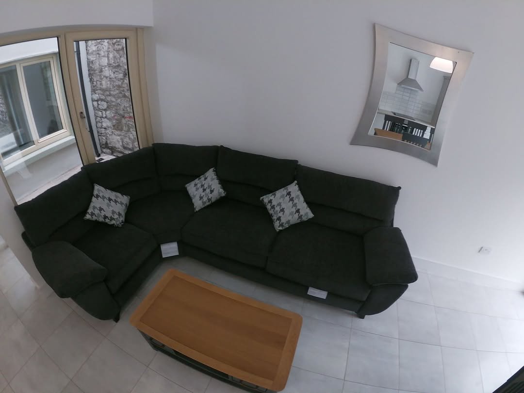 Living room with dark green sectional sofa, coffee table, and mirror.