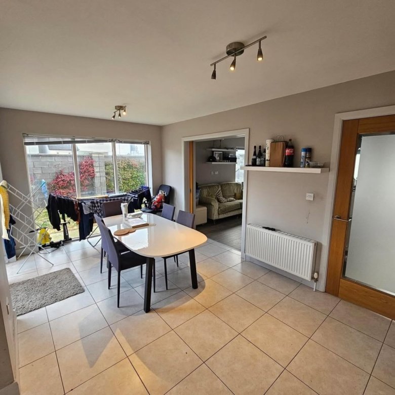 Bright dining area with table, chairs, radiator, and view to garden.