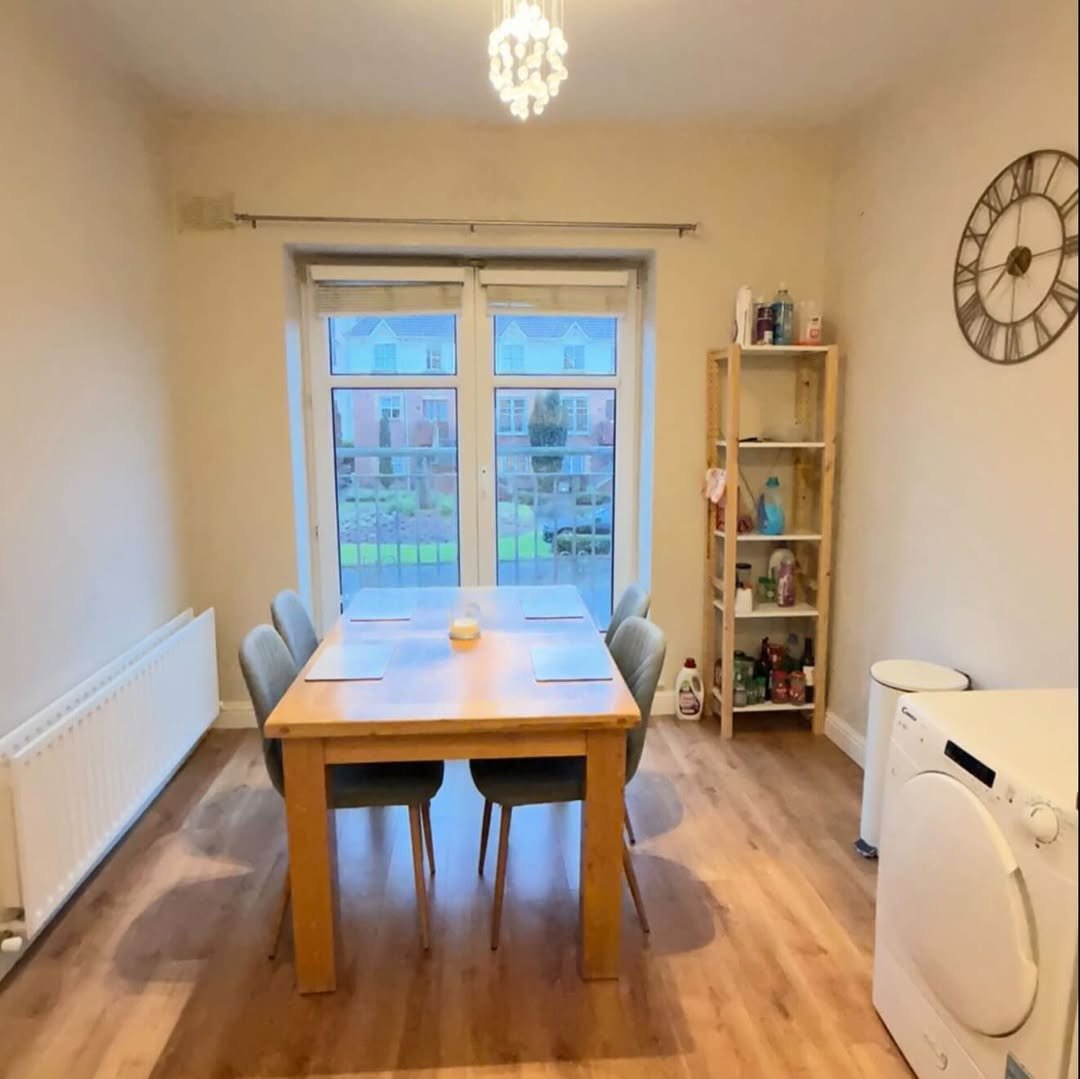 Dining room with table, chairs, shelving, and washing machine. Natural light from patio doors.