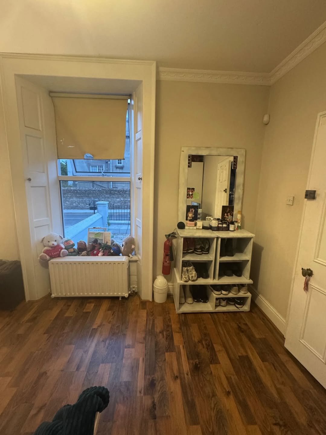 Entryway with shoe rack, mirror, radiator, and window with teddy bears.