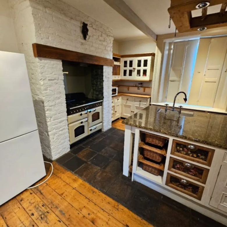 Farmhouse kitchen with brick oven, island, and wooden floors.