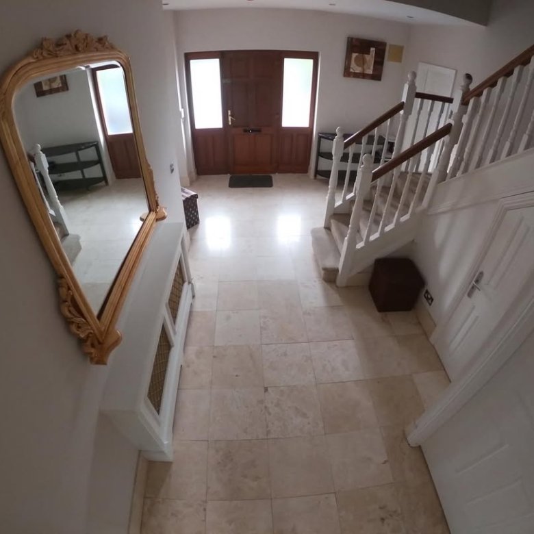Foyer featuring tile flooring, wooden door, staircase, mirror, and white console table.