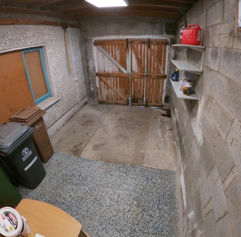 Garage interior with bins, shelves, and wooden doors.