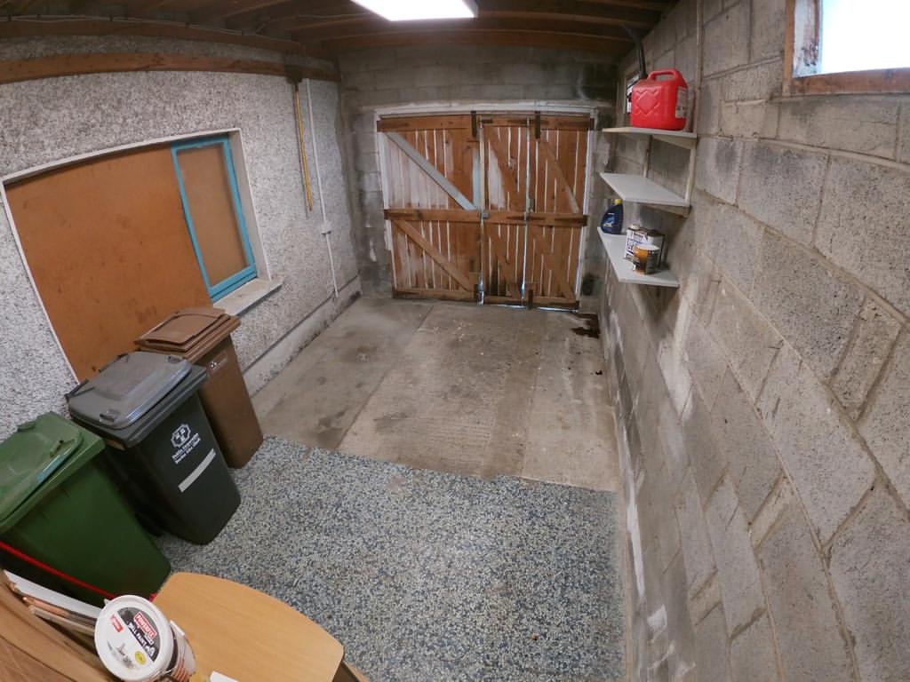 Garage interior with bins, shelves, and wooden doors.