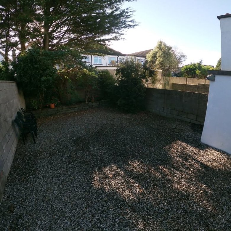 Gravel-covered courtyard with stone walls, trees, and chairs.