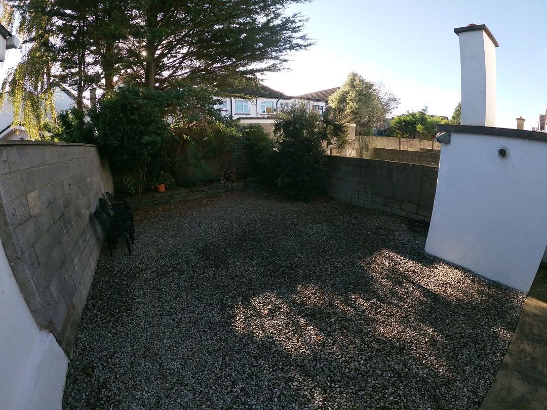 Gravel-covered courtyard with stone walls, trees, and chairs.