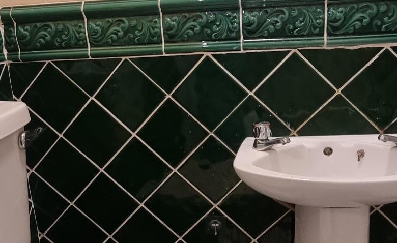 Green tiled bathroom with pedestal sink and toilet. Vintage style bathroom.