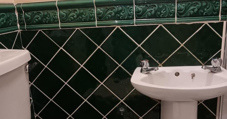 Green tiled bathroom with pedestal sink and toilet. Vintage style bathroom.