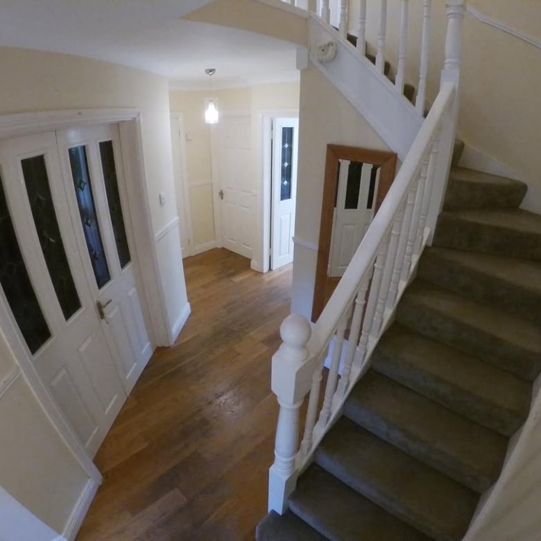 Hallway with staircase, white paneled doors, and wood flooring in a home interior.