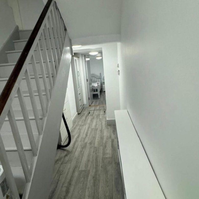 Hallway with stairs, white walls, and light gray wood-look flooring.