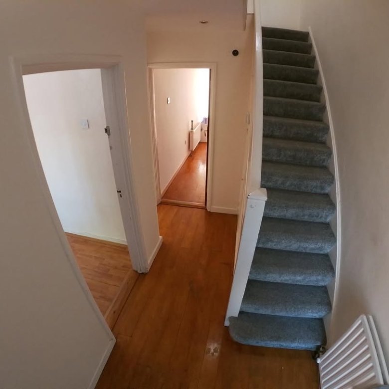 Hallway view with stairs, wooden floors, and doorways leading to other rooms.