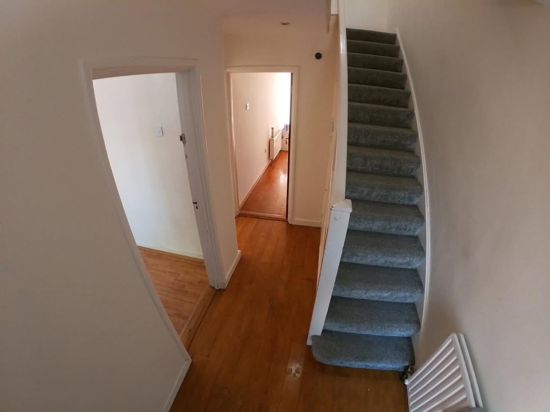Hallway view with stairs, wooden floors, and doorways leading to other rooms.