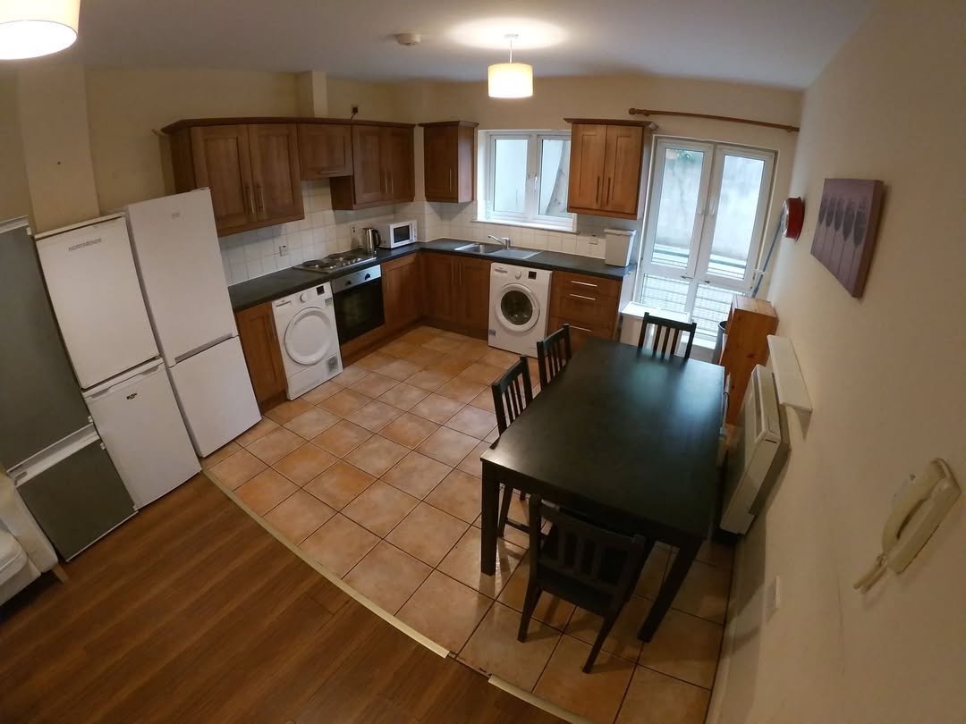 Kitchen and dining area with appliances, table, and chairs.