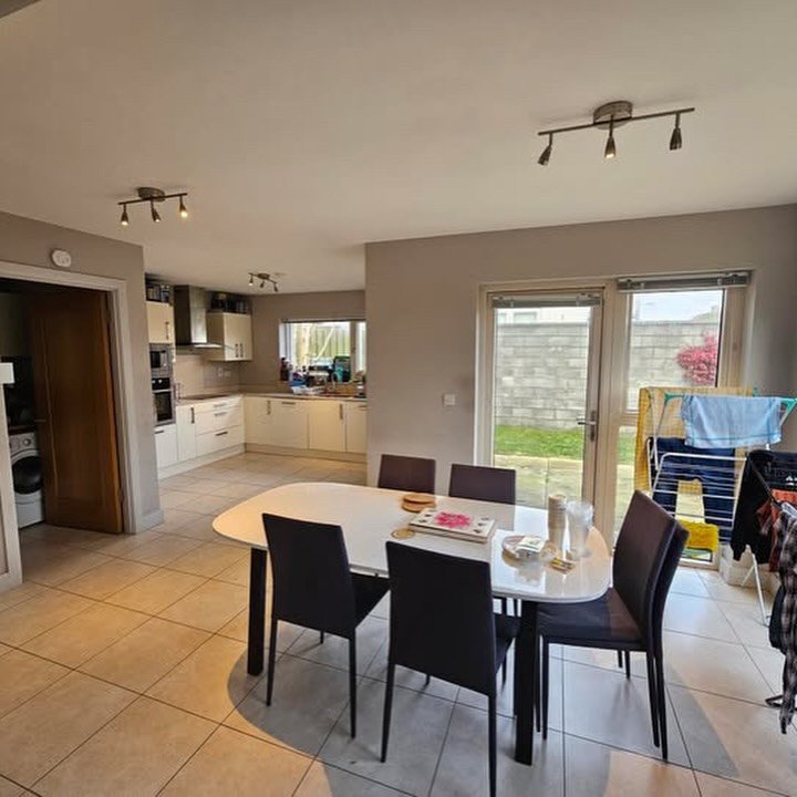 Bright kitchen and dining area with table, chairs, and open doorway to laundry room.