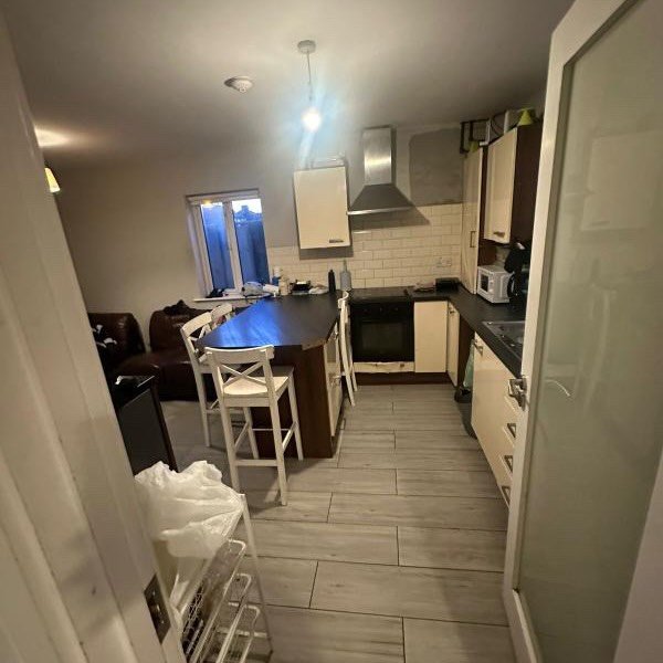 Kitchen with island, white cabinets, and wood-look tile flooring. Bright interior.
