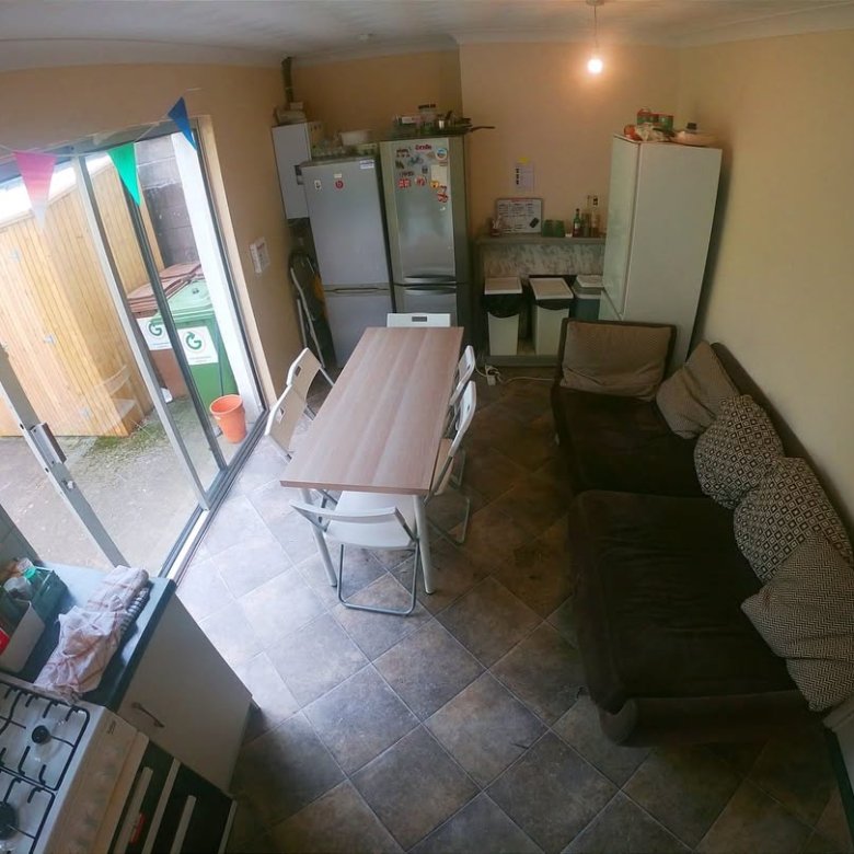 Cozy kitchen-living area with sofa, table, and open door to garden.