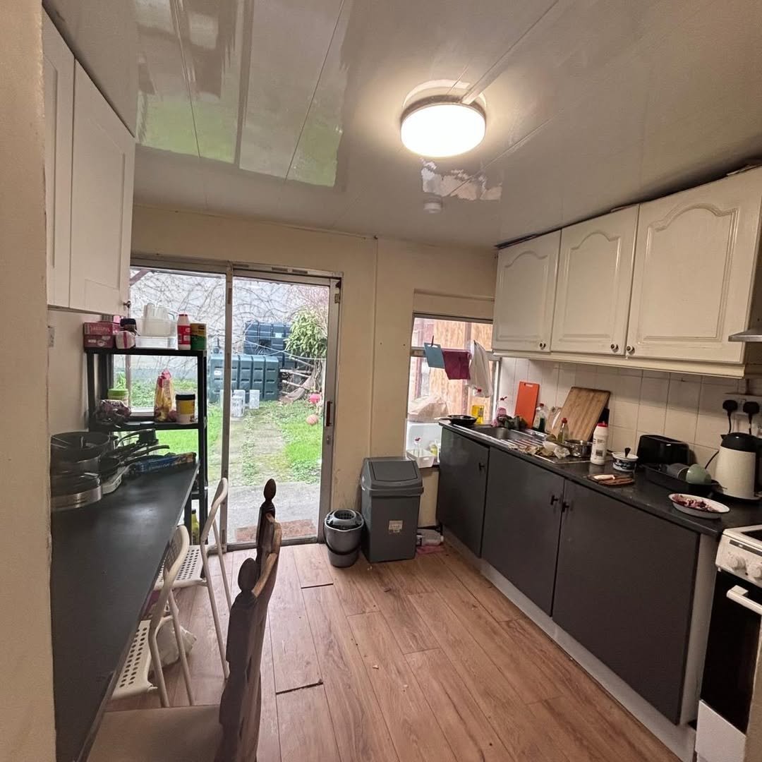 Kitchen with white cabinets, dark countertops, and a view to the garden.