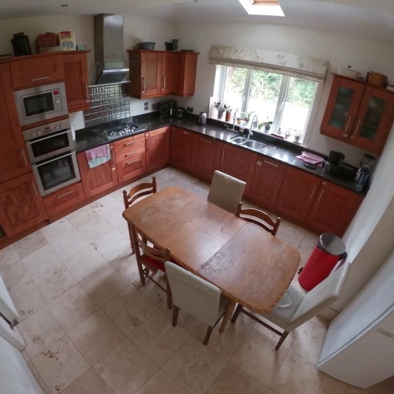 Cozy kitchen with wood cabinets, dining table, tile floor, and natural light from a window.