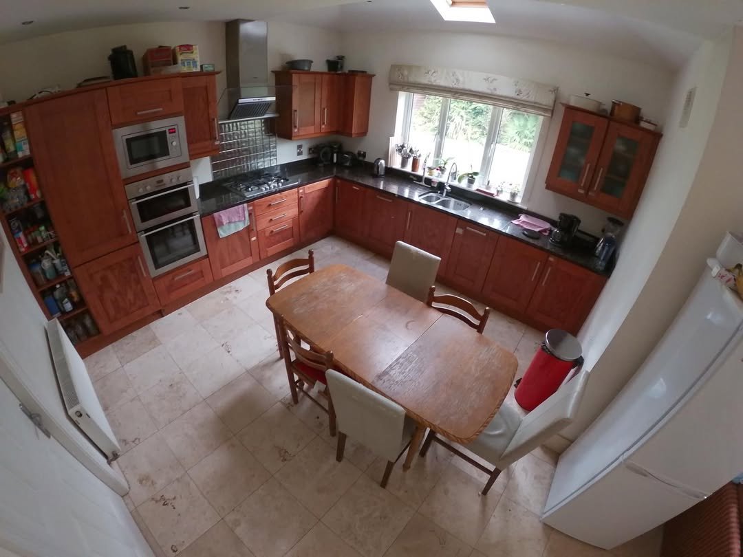 Cozy kitchen with wooden cabinets, dining table, and tile flooring. Natural light from the window.