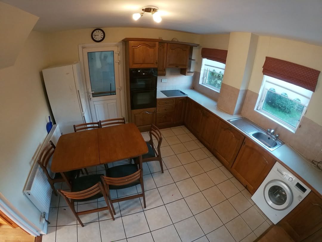 Cozy kitchen with wooden cabinets, dining table, white appliances, and tile floor.