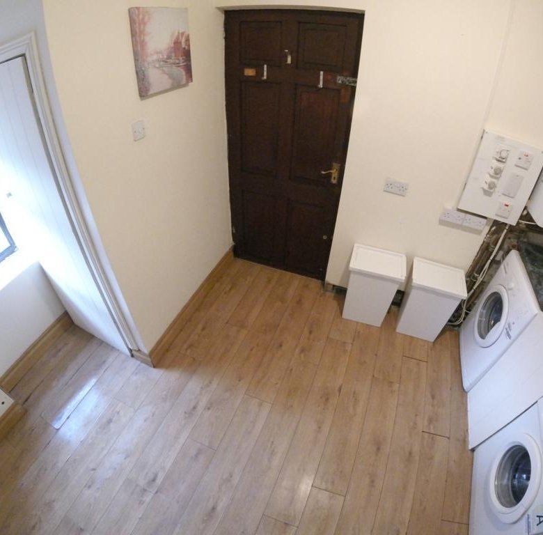 Laundry room with washer, dryer, sink, window, and dark wood door.