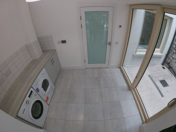 Laundry room with washer, dryer, white door, and sliding glass door to outdoors.