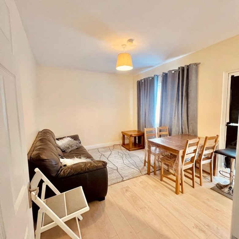 Living room with brown sofa, wooden dining set, and light wood floors.