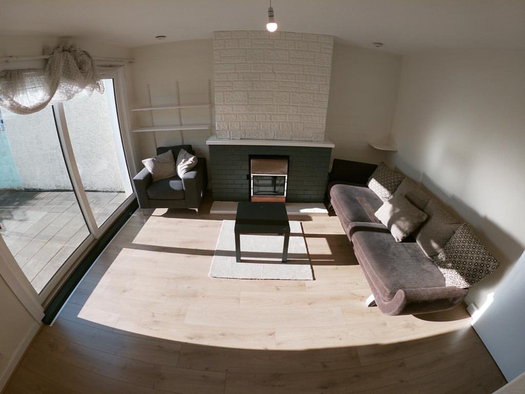 Living room with gray sofa, chair, fireplace, light wood floors, and sliding glass door.
